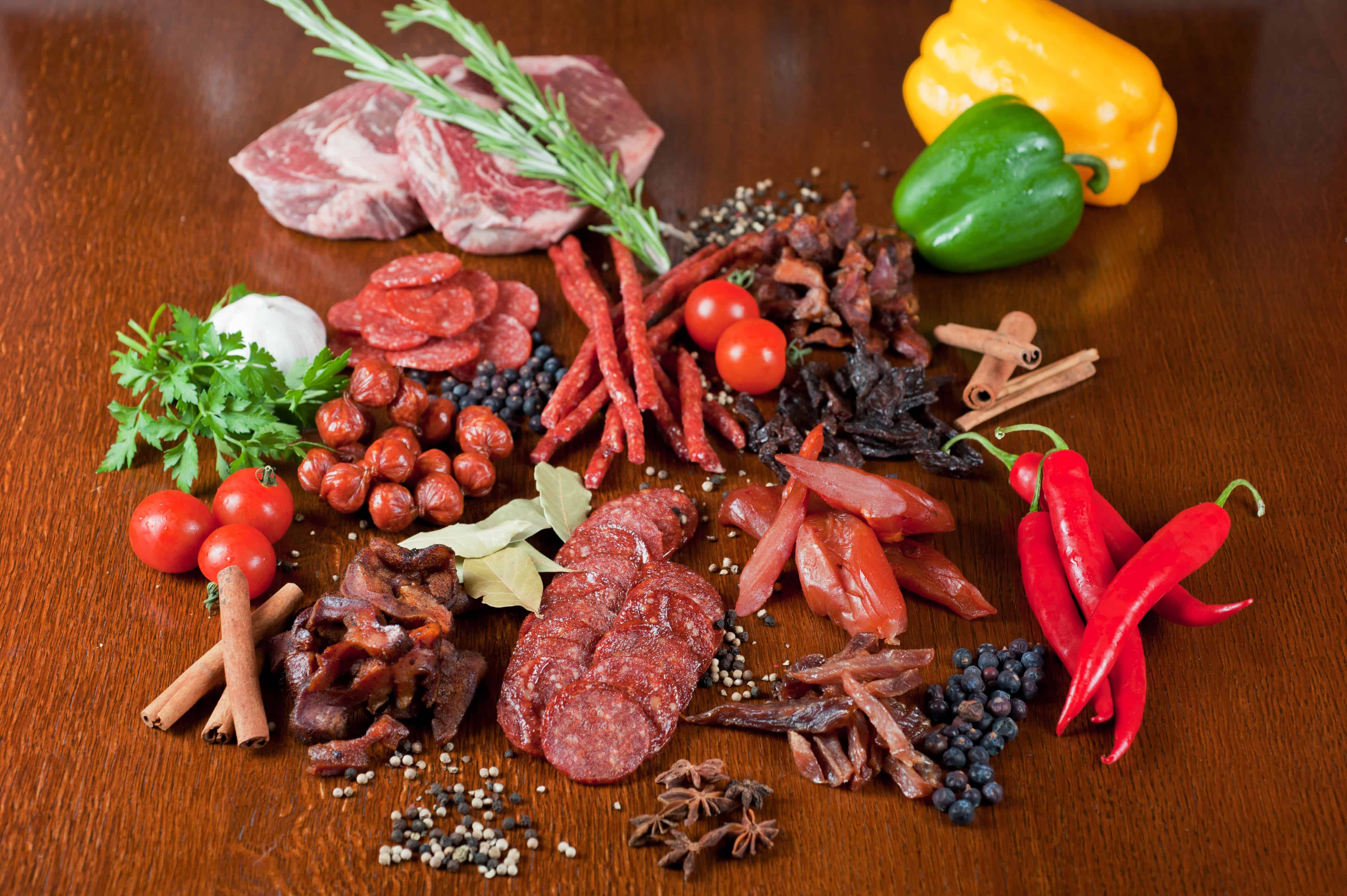different sausage and meat on a celebratory table with spices and vegetables