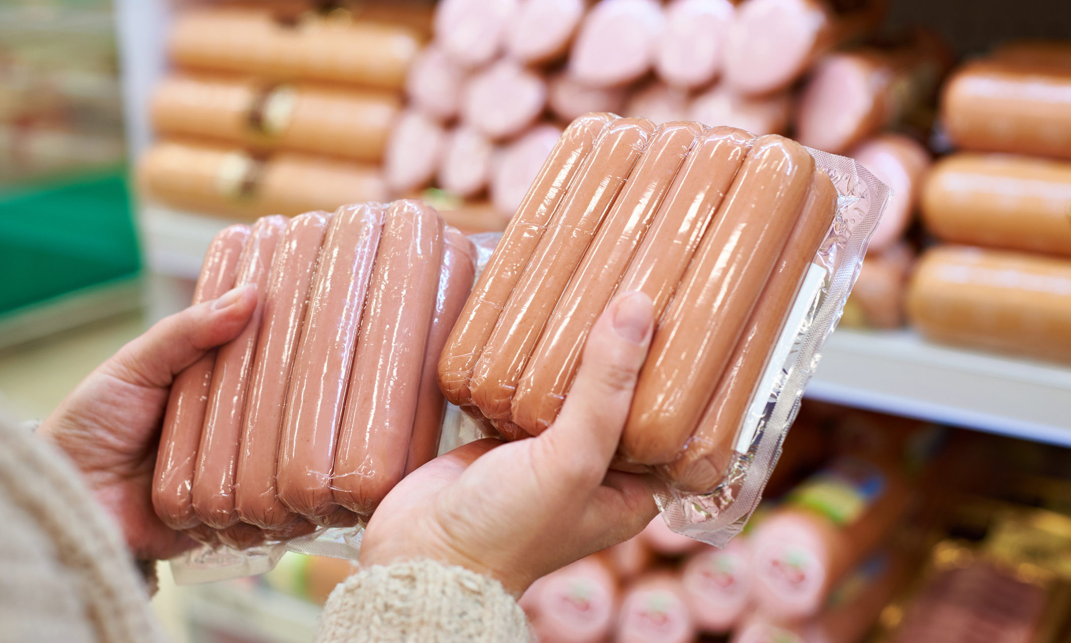 Woman chooses sausages in a vacuum package at the grocery store